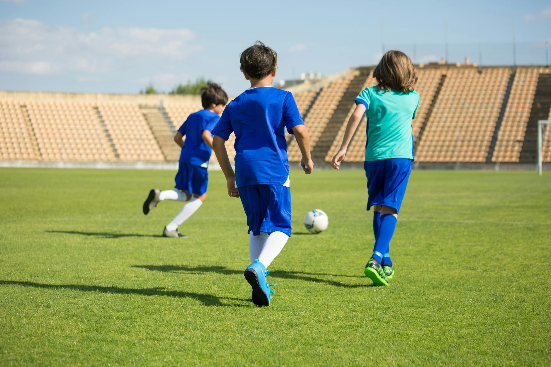 three boys playing soccer on a soccer field